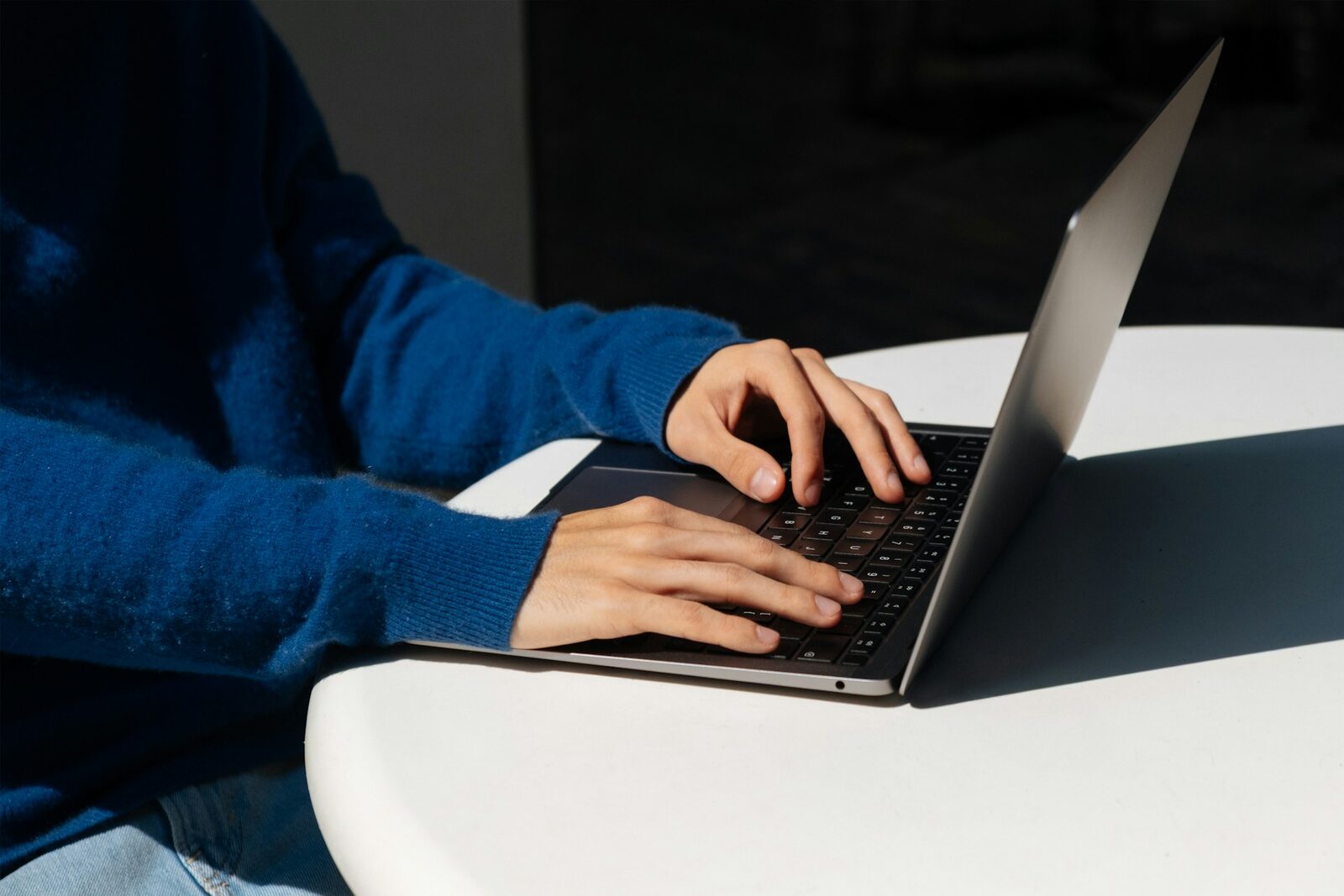 Person in a blue sweater typing on a laptop, representing routine WordPress core and plugin updates